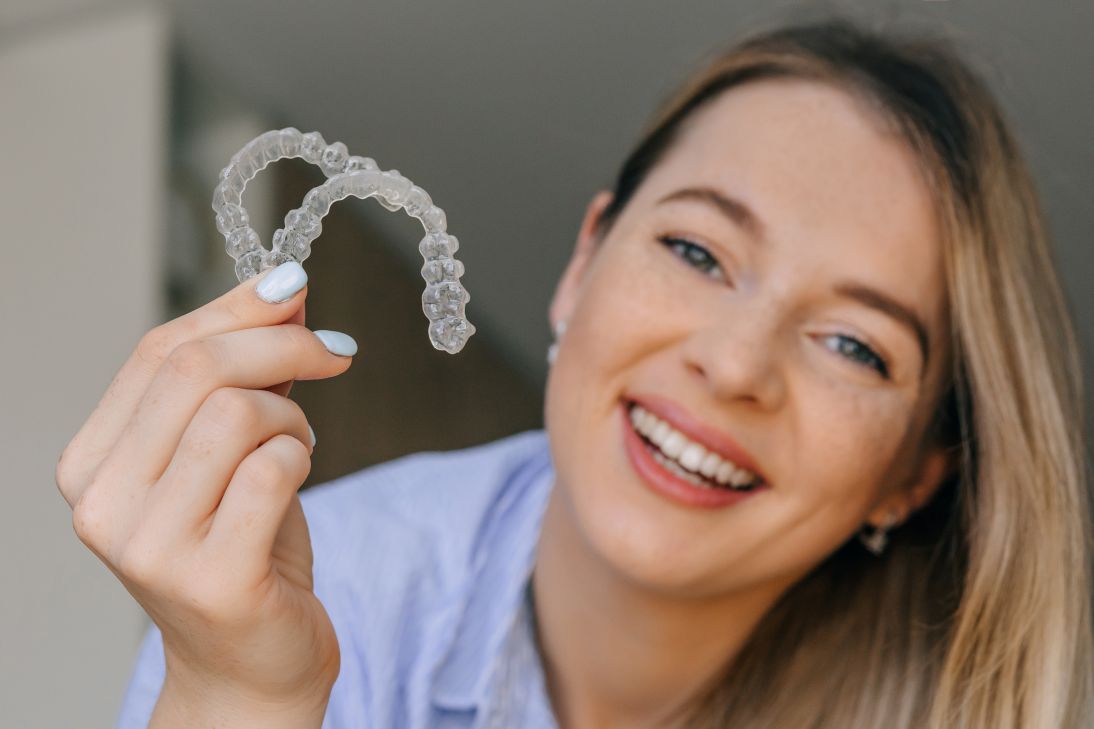 A woman holding two clear aligners