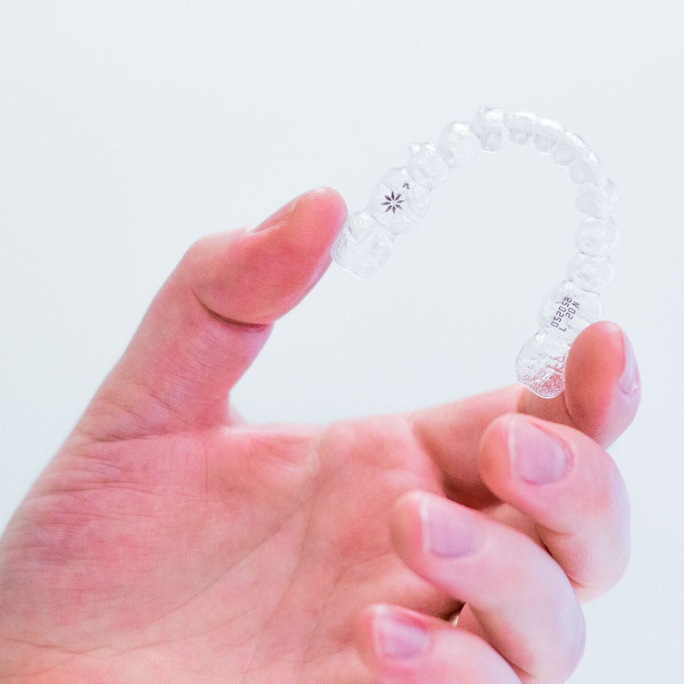 Hand holding clear aligners provided by an orthodontist in Stephenville